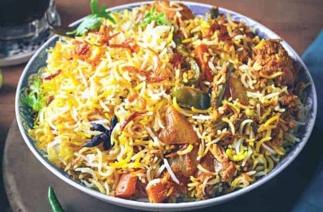 A steaming bowl of vibrant vegetable biryani garnished with fried onions and fresh cilantro, showcasing the flavorful fare offered by engagement catering services near me in Bangalore.