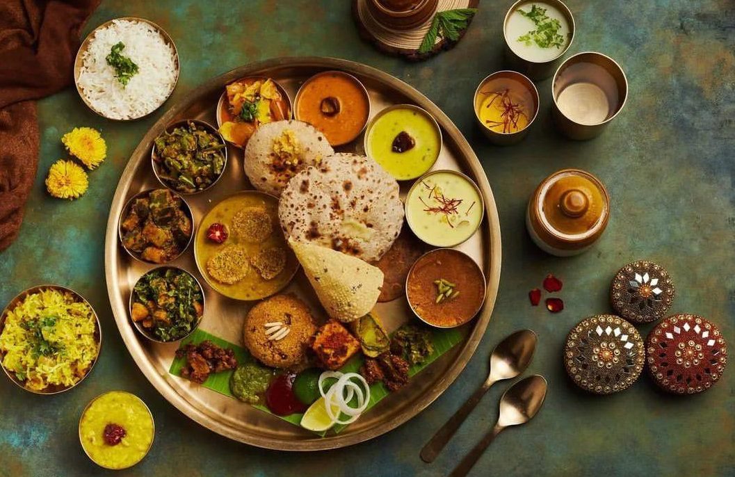 A vibrant Indian thali spread on a brass plate featuring soft chapatis, fluffy rice, an array of small bowls with colorful curries and chutneys, crisp papad, and sweet pongal—capturing the festive flair of engagement catering services near me Bangalore.