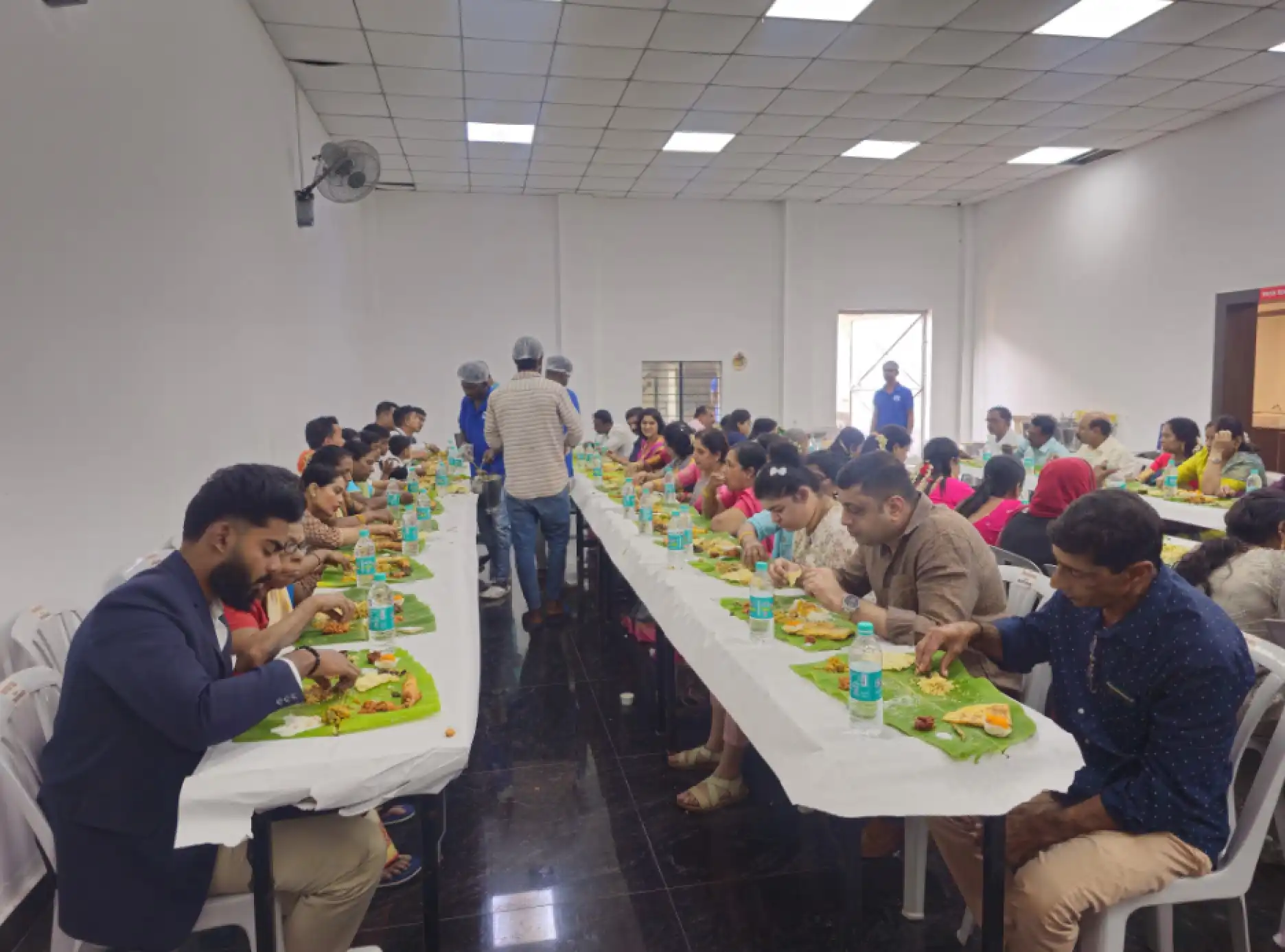 Caterers serving banana leaf meals to guests during a function
