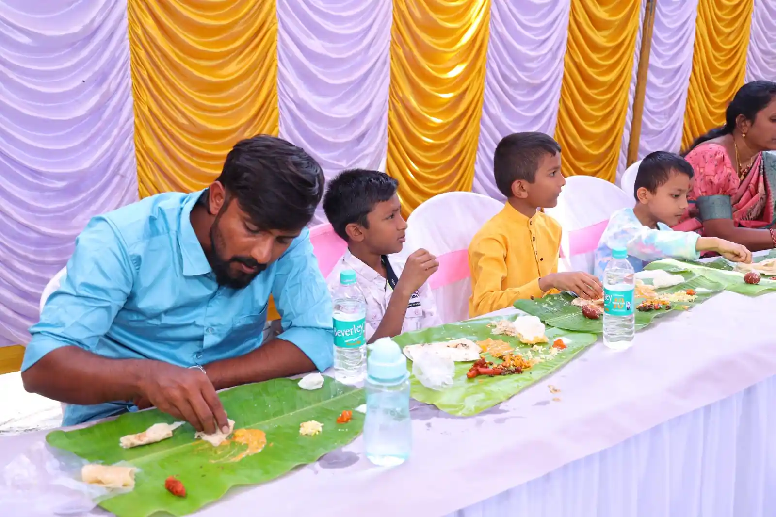 Large community gathering enjoying lunch on banana leaves