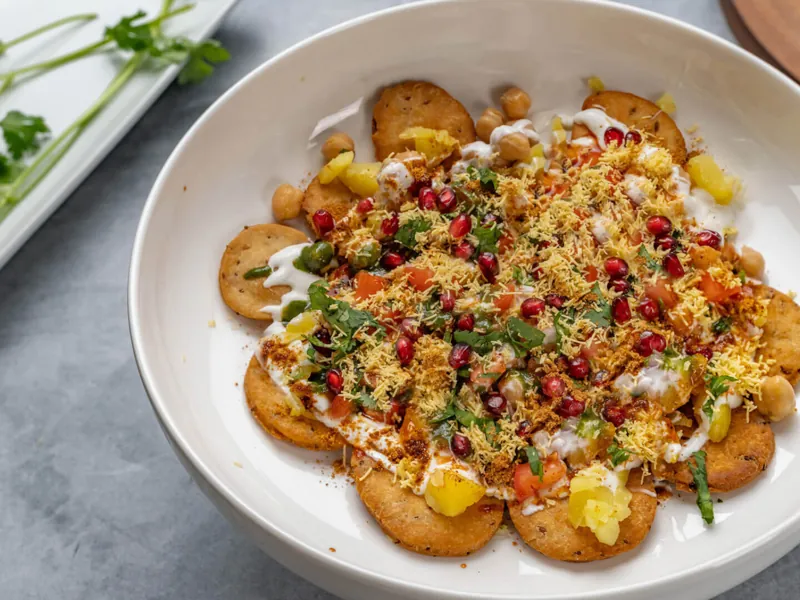 Indian chaat catering service with papdi chaat topped with curd, chutneys, sev and pomegranate