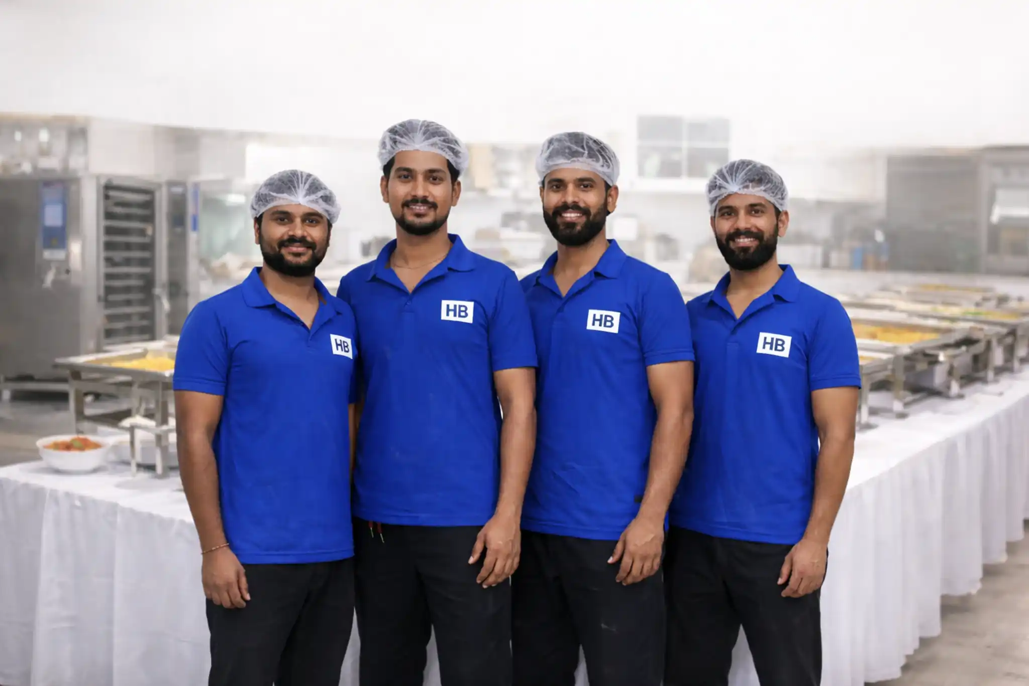 Hiibangalore caterers team in blue uniforms standing in hygienic catering kitchen in Bangalore