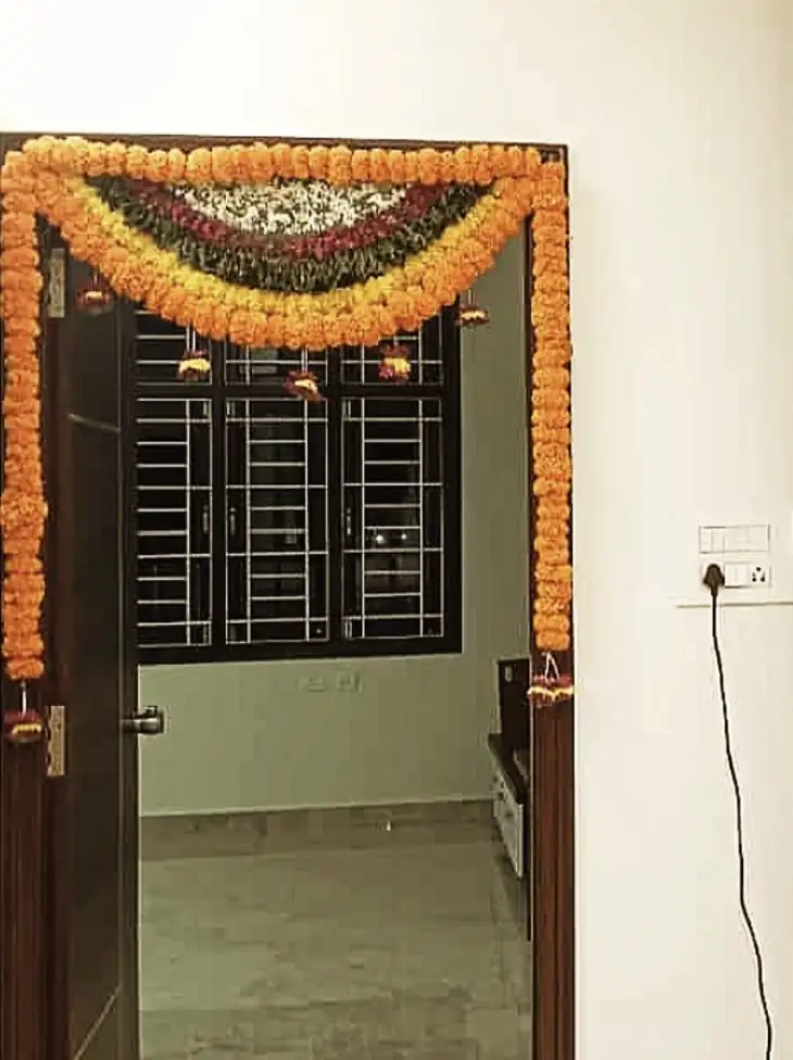 Fresh marigold flower decoration on bedroom door for housewarming ceremony in Bangalore.