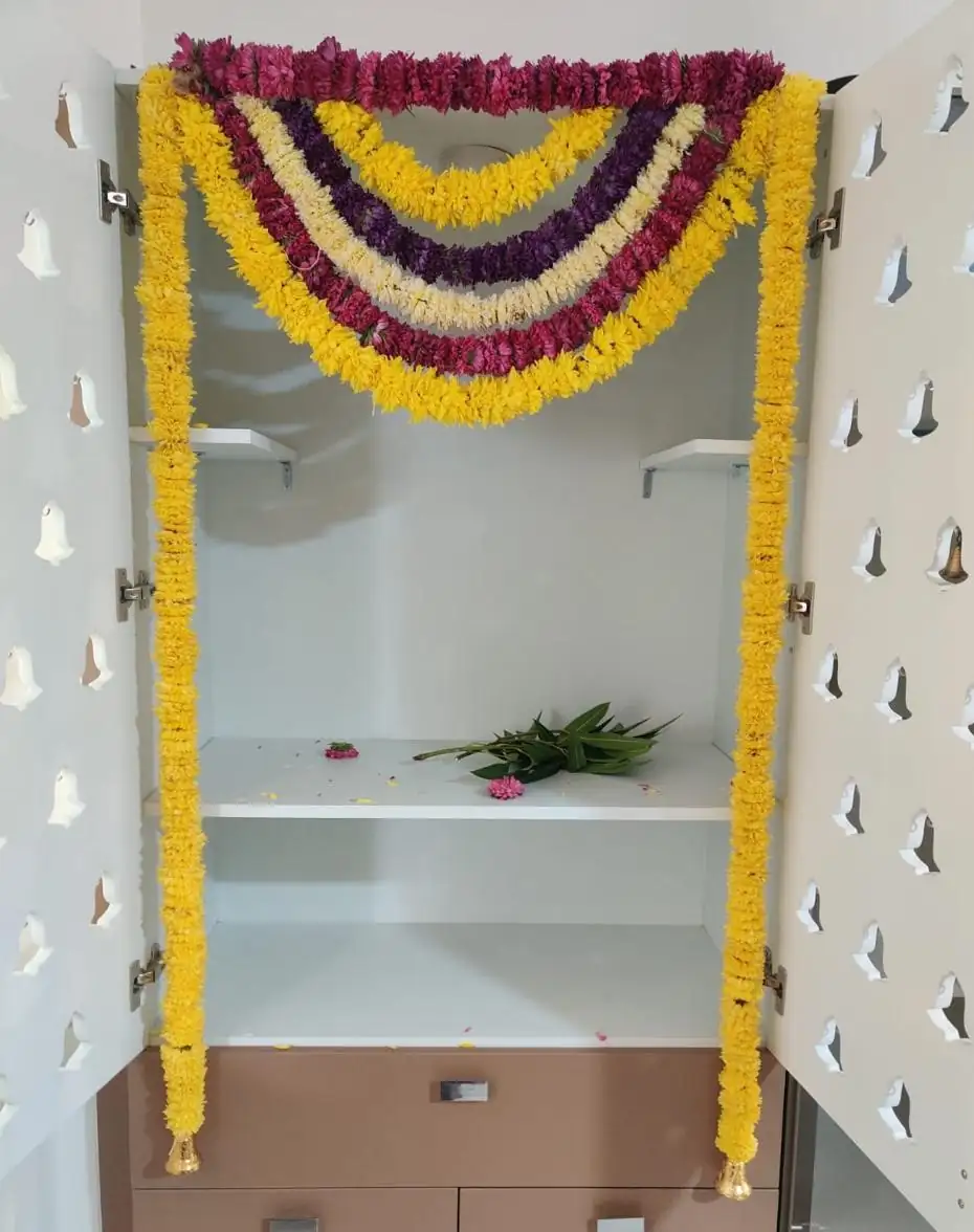 Housewarming puja room decorated with traditional marigold and rose flower garlands
