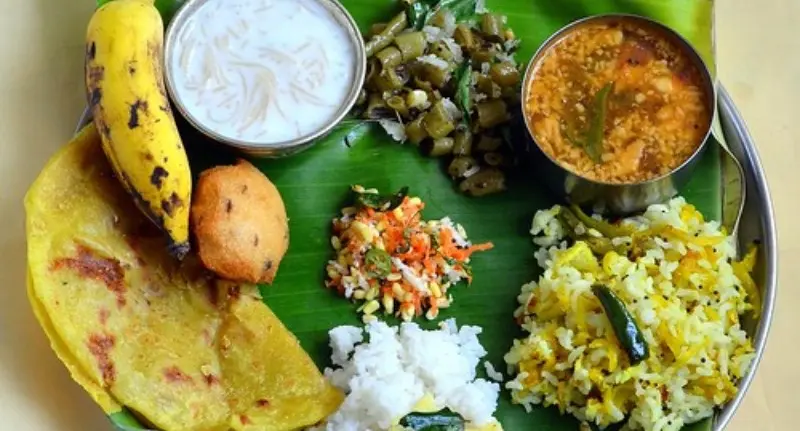 Traditional Karnataka style vegetarian meal served on a banana leaf with rice, sweets, curries and sides.
