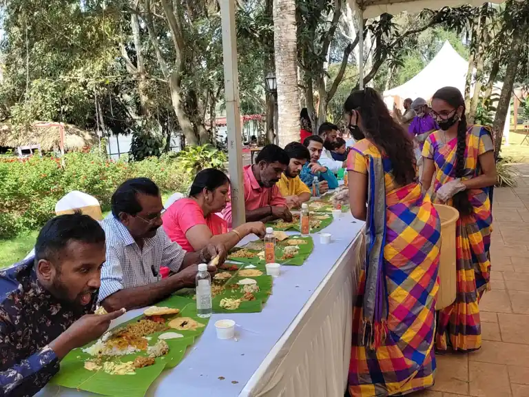 Large event food service with guests dining on banana leaves at an outdoor vegetarian catering event