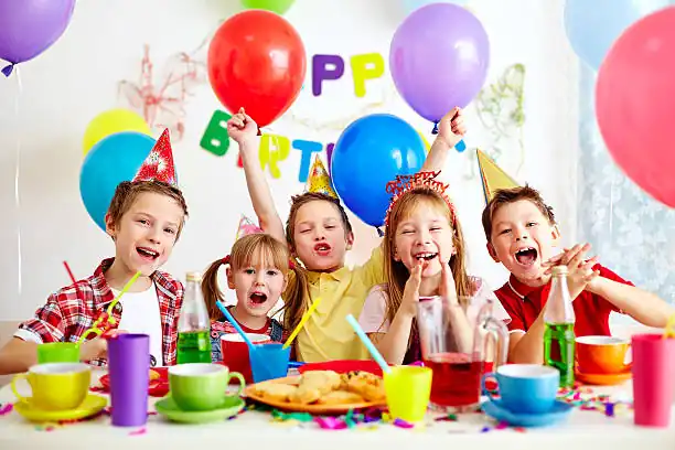 Happy children celebrating birthday party with balloons and party hats organised by kids birthday party planners in Bangalore