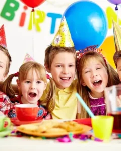 Happy children celebrating birthday party with balloons and party hats organised by kids birthday party planners in Bangalore