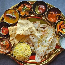 North Indian vegetarian catering thali with naan, rice, curry, gulab jamun and assorted dishes served on platter