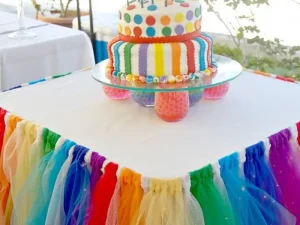 Colourful birthday cake table decoration with rainbow table skirt in Bangalore