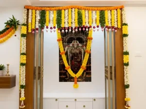 Gruhapravesham pooja room door decorated with yellow and white flower garlands in Bangalore