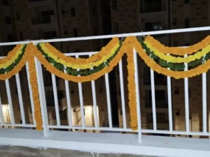 Housewarming balcony decorated with yellow and orange flower garlands in Bangalore