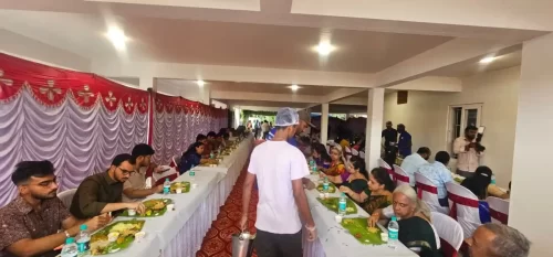 Large gathering enjoying banana leaf meals at a community catering event