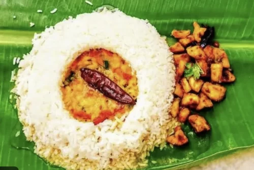 Rice served with Andhra pappu and side dishes on banana leaf