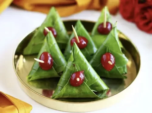 folded sweet paan decorated with cherries on a brass plate