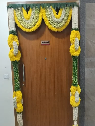 Elegant griha pravesh main door floral setup with fresh flowers