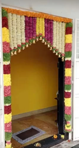 Griha pravesh main door flower arrangement ideas with marigold garlands