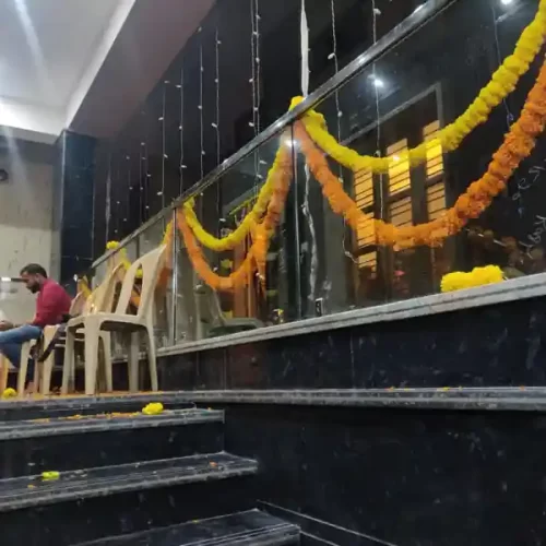 Glass railing decorated with marigold garlands and string lights for housewarming