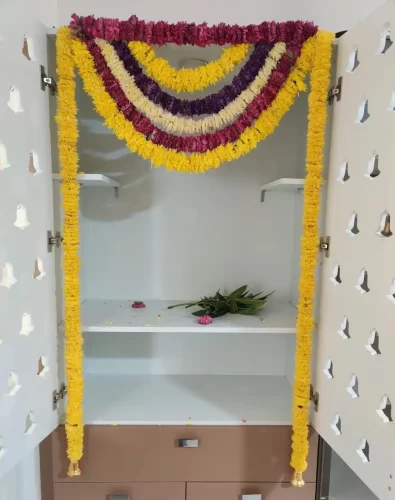 Housewarming puja room decorated with traditional marigold and rose flower garlands